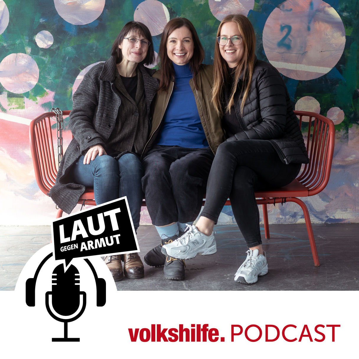 Drei Frauen sitzen lachend auf einer roten Bank vor bunter Wand. Logo des „Laut gegen Armut“-Podcasts und Schriftzug „volkshilfe. PODCAST“ im Vordergrund.